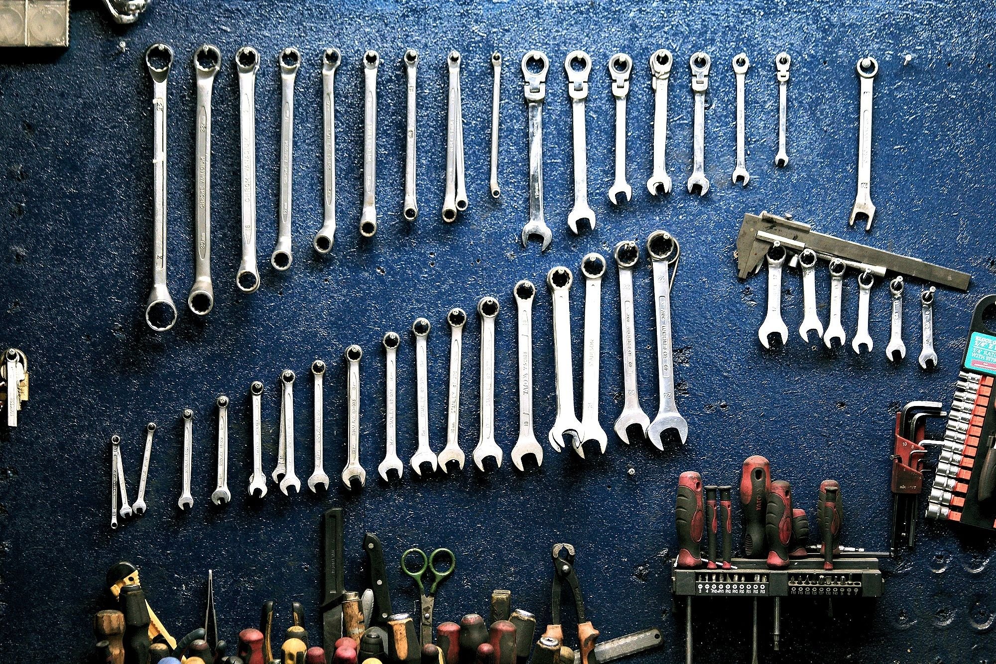 Wrenches hung in graduated rows on a dark blue pegboard wall